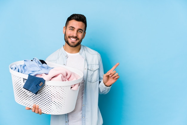 young-handsome-man-doing-laundry-isolated-smiling-pointing-aside-showing-something-blank-space_1187-121623